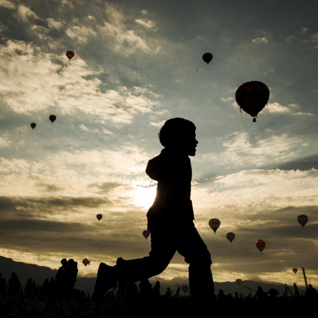 Một cậu bé chạy ngang cánh đồng nơi có hàng trăm khinh khí cầu đang được thả lên trời trong ngày đầu tiên của lễ hội Albuquerque International Balloon Fiesta, ở New Mexico, 03/10/2015.